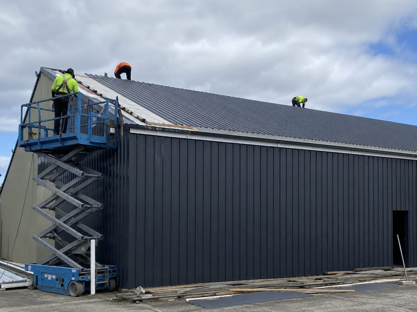 Industrial roofers reroofing a large shed in Whangarei
